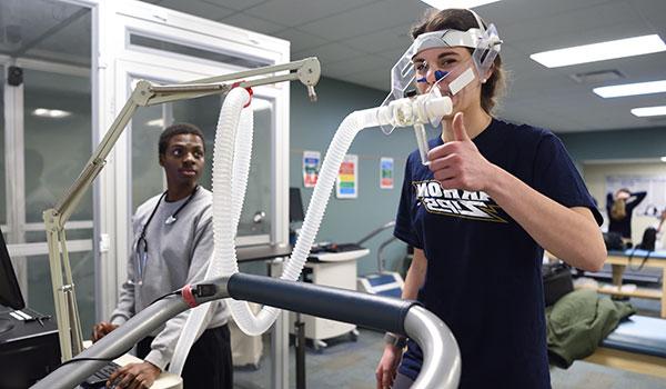 Student monitoring health stats while another student exercises.